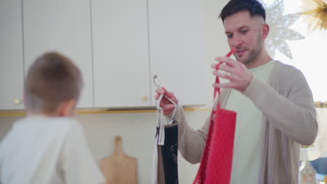 dad helps son put on kitchen apron for baking cookies