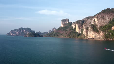 Bote-De-Cola-Larga-Navegando-En-El-Mar-Debajo-De-La-Costa-Del-Acantilado-De-Montaña-De-Tailandia