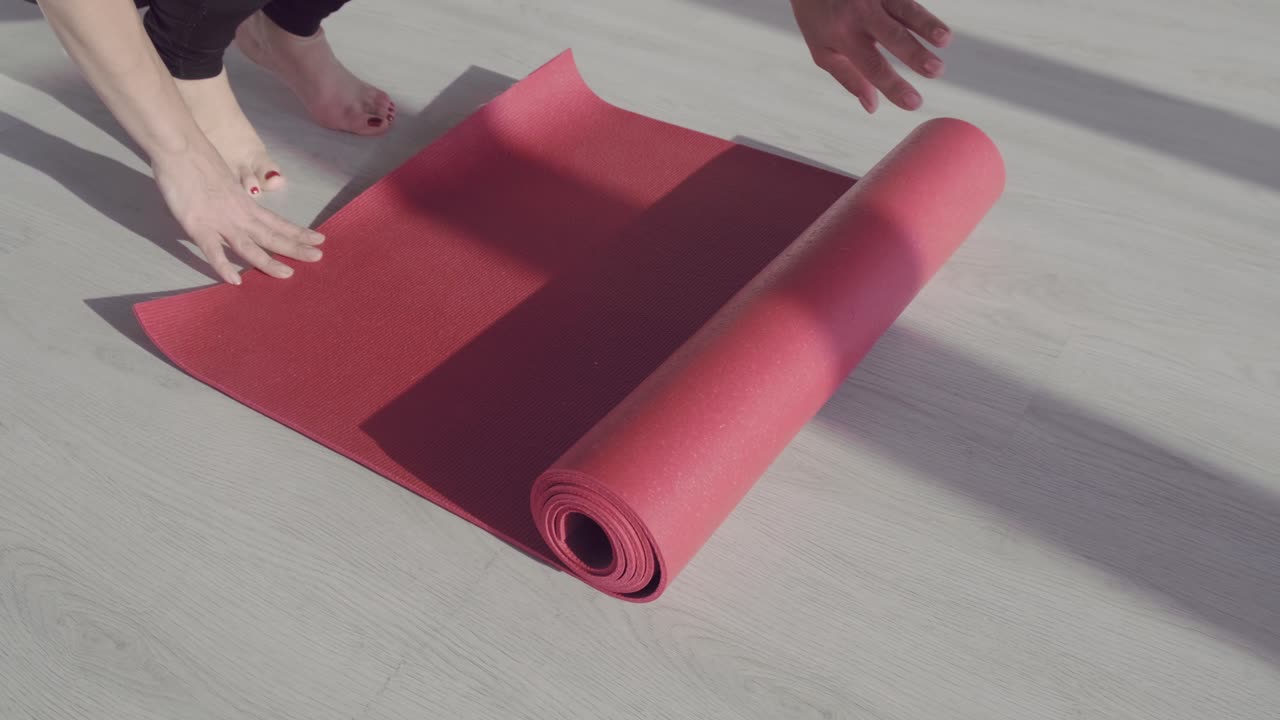 Unrolling a Red Yoga Mat on a Light Wooden Floor