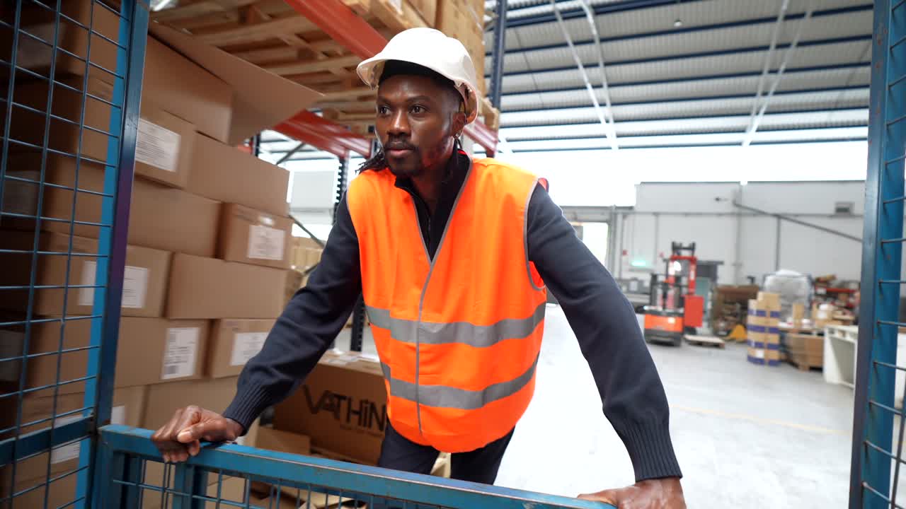 Warehouse worker pushing cart through aisles of boxes