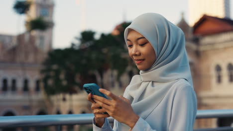 young muslim woman using smartphone outdoors