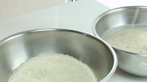 chicken being dipped in sauce and breading