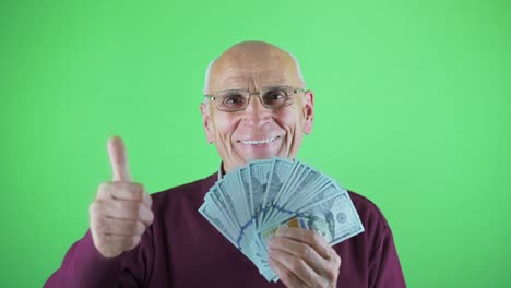 hombre de edad en gafas sosteniendo dólares en la mano y mostrando el signo ok