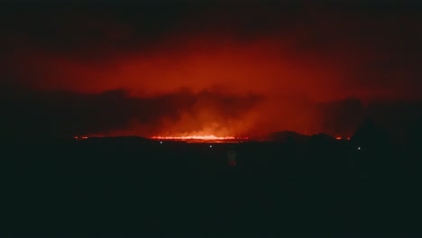 volcanic eruption at night with glowing lava flow in the distance