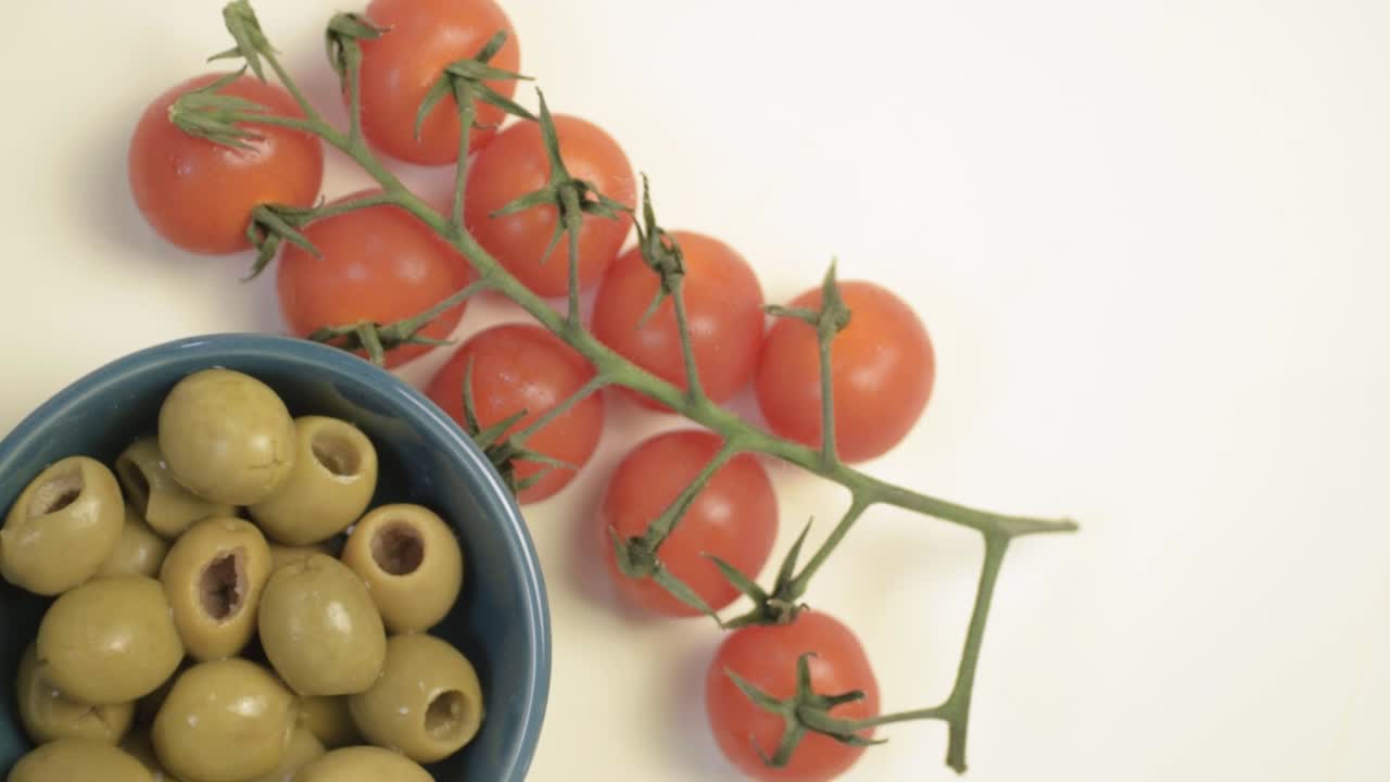 Green olives and cherry vine tomatoes rotating medium flat lay shot