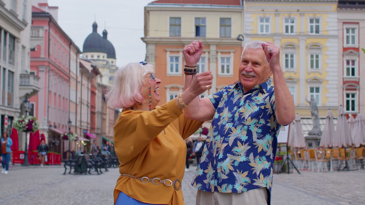 Elderly stylish couple tourists man woman celebrate success win scream rejoices doing winner gesture