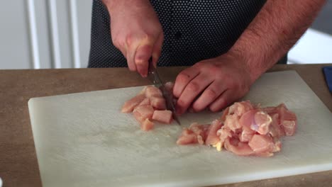 pollo en cubos en una tabla de cortar blanca