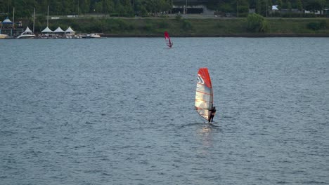 la luz del sol se refleja en la vela de una persona haciendo windsurf en el río han cerca del parque ttukseom al atardecer