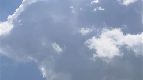 성난 구름이 화면 왼쪽 하단에서 오른쪽 상단으로 이동하고 있으며, 푸른 하늘과 태양의 일부가 있습니다.