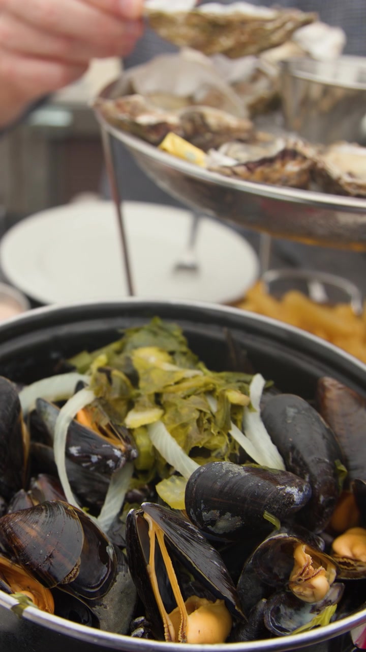 Close-up of moules-frites and oysters served outdoors, natural daylight, handheld camera, relaxed atmosphere