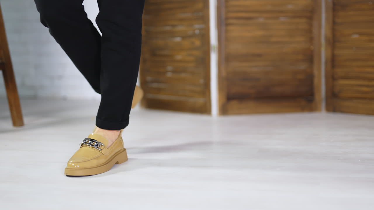 Beige lacquered shoes on plain soles demonstration. Model walks back and forth presenting new fashionable footwear. Blurred backdrop.