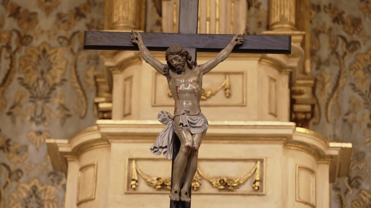 Close up of a crucifix with Jesus Christ mounted on a decorative gold church altar background