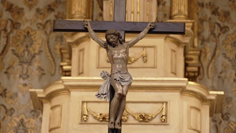 close up of a crucifix with jesus christ mounted on a decorative gold church altar background