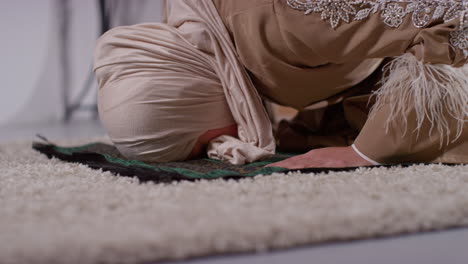 close up of muslim woman wearing hijab at home praying kneeling on prayer mat 5