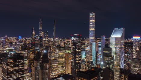 Forwards-fly-around-tall-office-building-with-glossy-reflecting-facade.-Night-hyperlapse-of-modern-downtown-skyscrapers.-Manhattan,-New-York-City,-USA