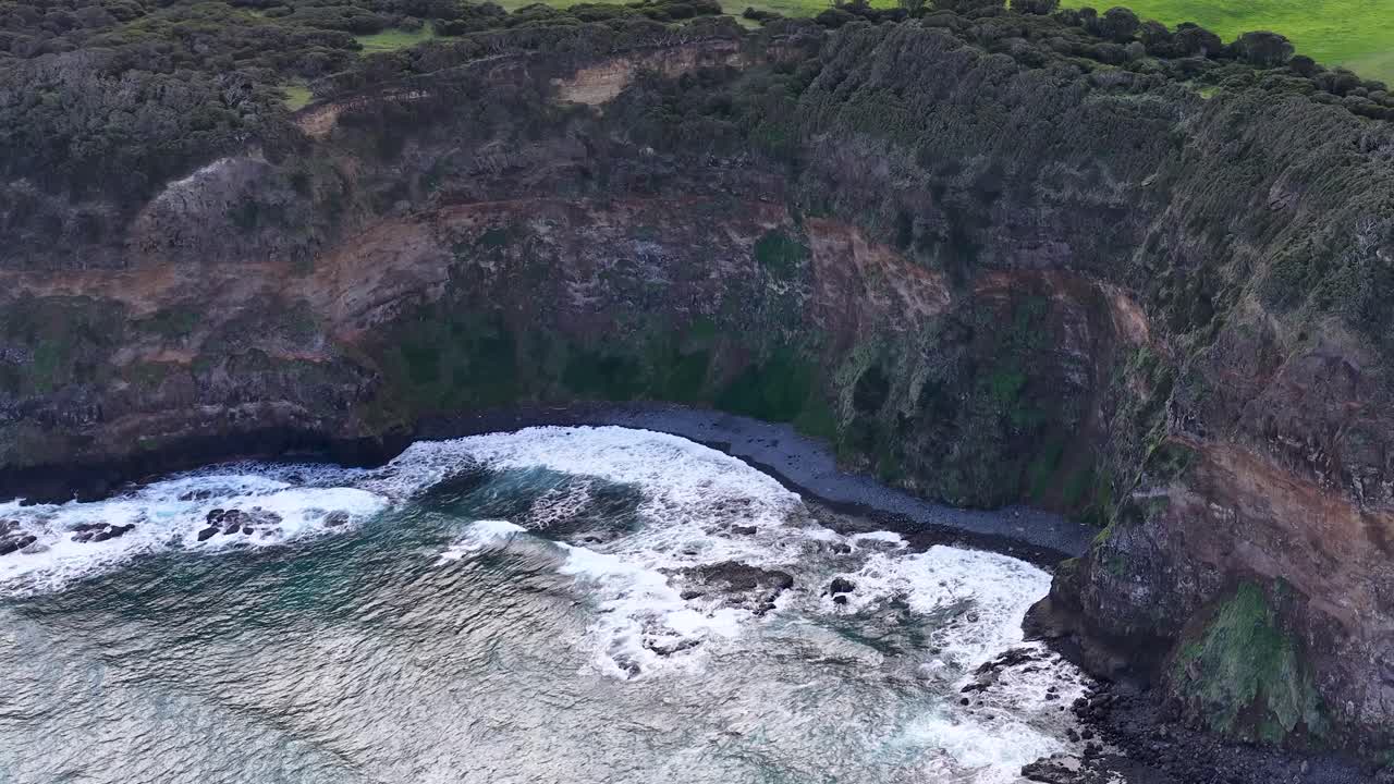 Drone camera glides above Cape Schanck cliffs, revealing dramatic shoreline, waves, and rocky terrain