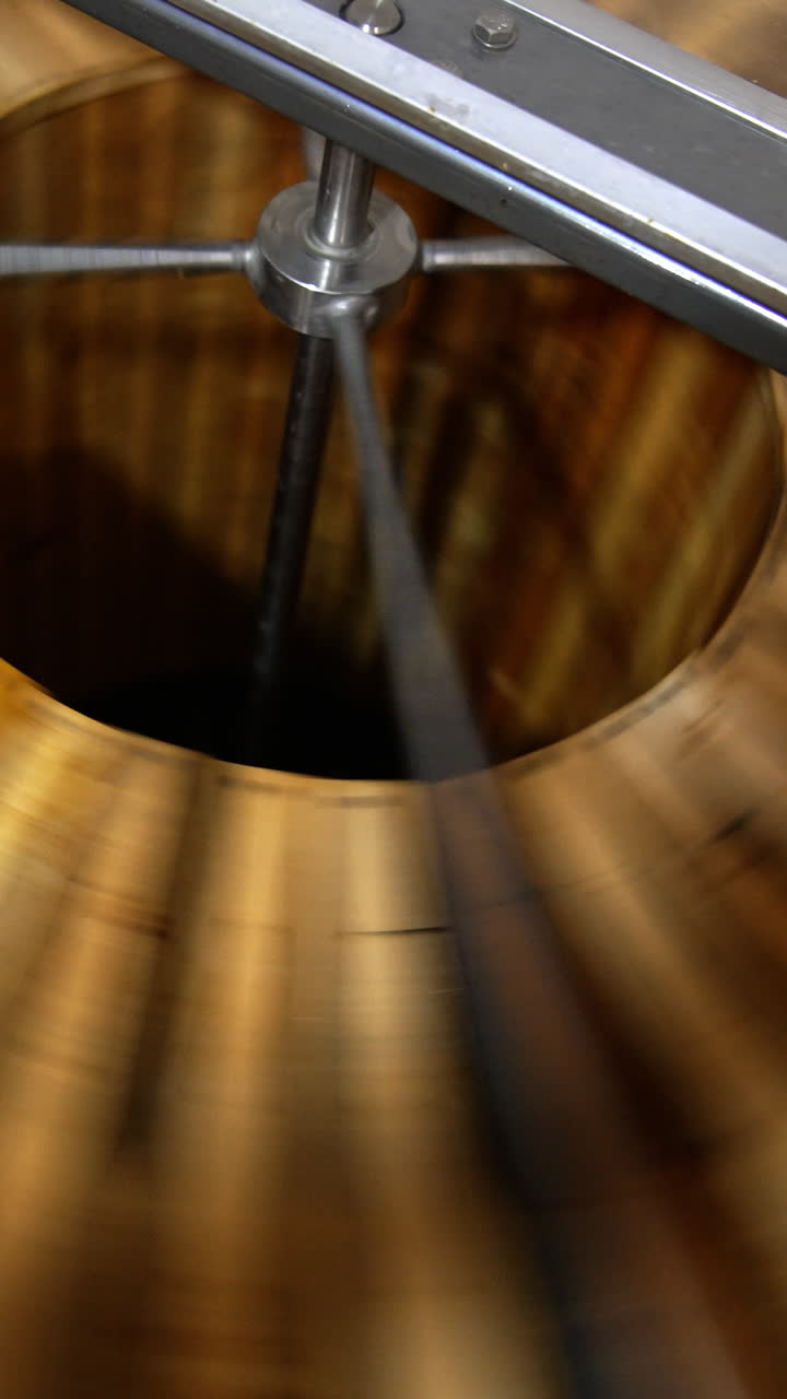 Lots of wooden frames being rotated in the centrifuge machine. Process of honey extraction in special apiary equipment. Close up. Top view. Vertical video