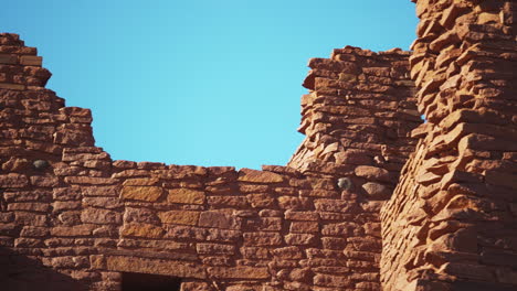 panning shot of old ruins of wukoki pueblo on sunny day