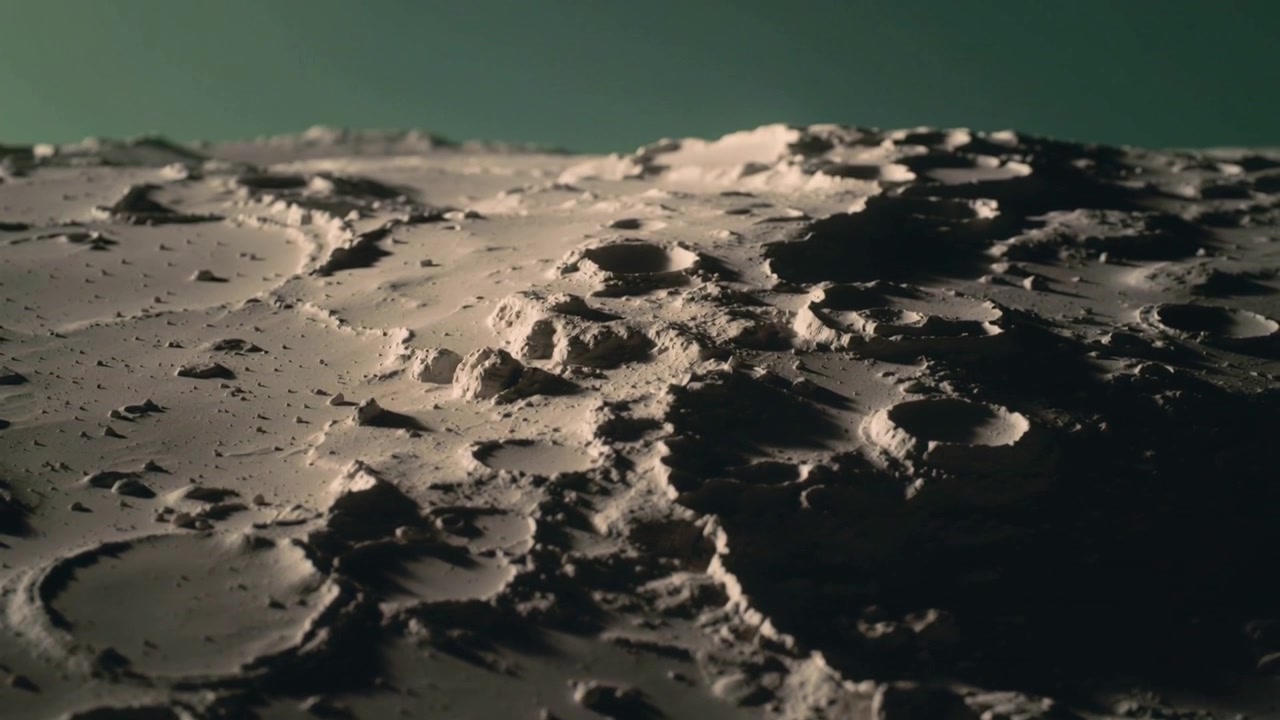 Panning camera revealing cratered plain with green backdrop for study, low light casting shadows