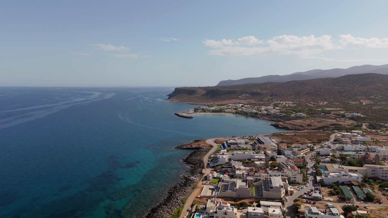 Aerial - scenic coastal town and blue waters with mountains in Crete Greece