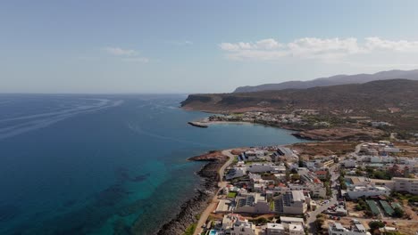 aerial - scenic coastal town and blue waters with mountains in crete greece