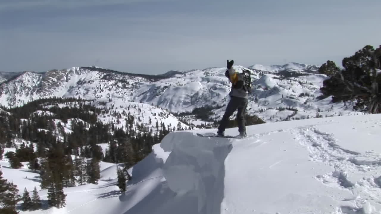 스노우보더가 슬로프에서 뛰어내려 짙은 가루에 착지하는 장면