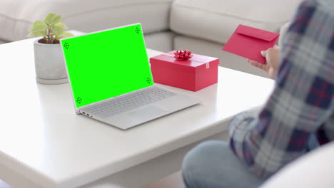 hombre caucásico sosteniendo un sobre y usando una computadora portátil con espacio de copia en la pantalla verde