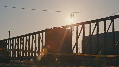 freight train moving in slow motion during golden hour with sun flares cinematic