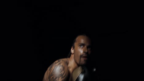 hombre alto y musculoso boxeando en la sombra en la oscuridad con la única luz en su rostro