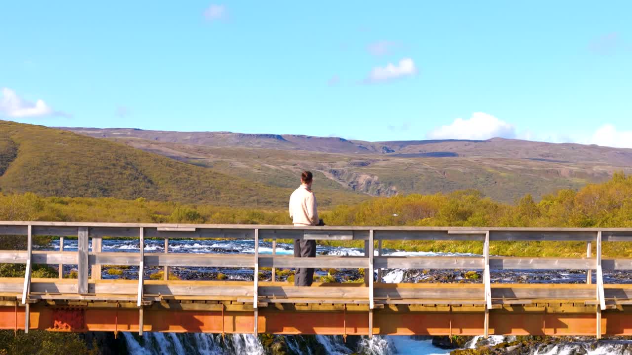 vista aérea, hombre de pie en el puente de vigilancia para la cascada escénica en gullfos, islandia