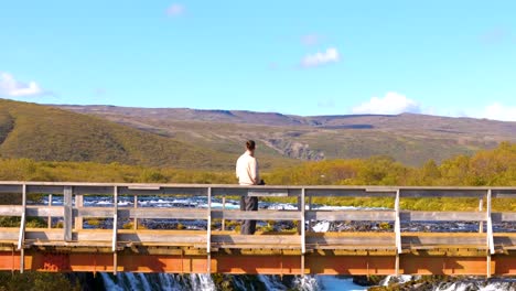 aerial view, man standing on lookout bridge for the scenic waterfall in gullfos, iceland