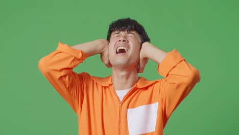 close up of stressed asian male prisoner screaming loud while standing on the green screen background