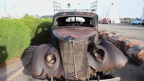 man inspecting rusted out vintage car