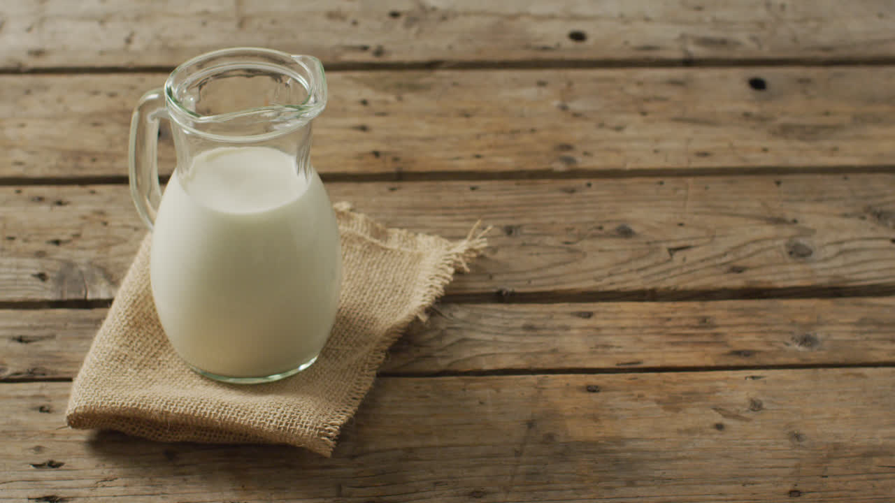 video de una jarra de vidrio de leche sobre un fondo de madera