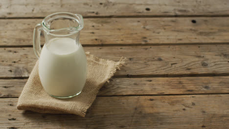 video of glass jug of milk on wooden background