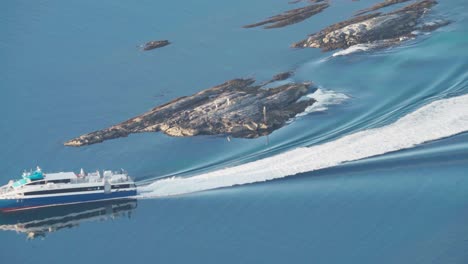 ferry boat leaving foamy backwash on calm waters of fjord in lovund island in norway