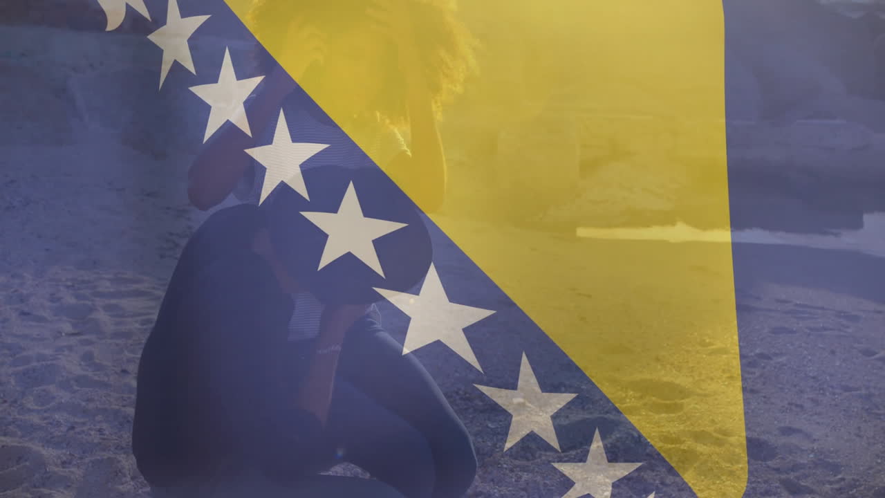 On sandy beach, person sitting with Bosnia and Herzegovina flag animation overlay