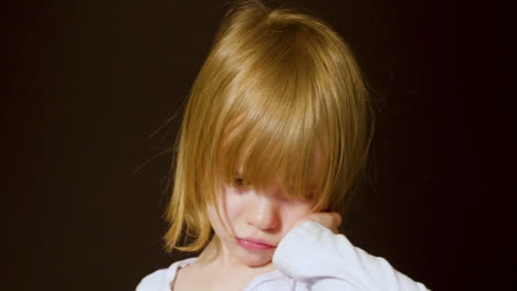 studio portrait of a cute little blonde girl looking sad