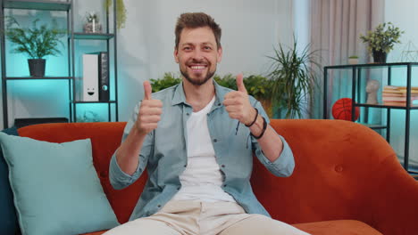 happy young man looking approvingly at camera showing thumbs up, like positive sign, good news