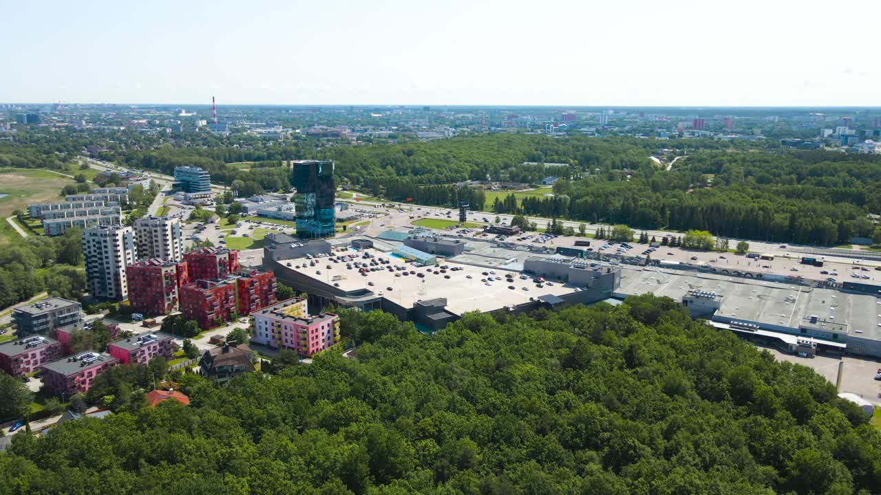 Gorgeous aerial drone footage panning over a luxury neighbourhood on Baltic ocean sea grassy and reed covered shoreline during a summer sunny day. Tall apartment buildings and a highway visible.