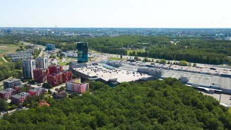 gorgeous aerial drone footage panning over a luxury neighbourhood on baltic ocean sea grassy and reed covered shoreline during a summer sunny day. tall apartment buildings and a highway visible.