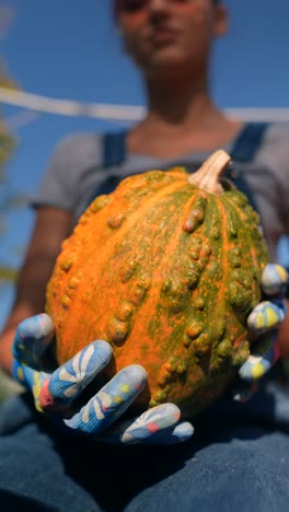 mujer sosteniendo una calabaza en el jardín