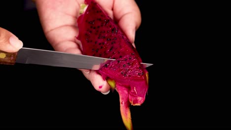 las manos cortando cuidadosamente la vibrante fruta del dragón