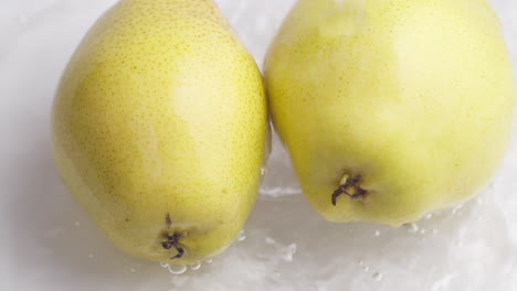 yellow pear on a blue dark background with drops of water rolling down the pear and flowing splashing with isolated background