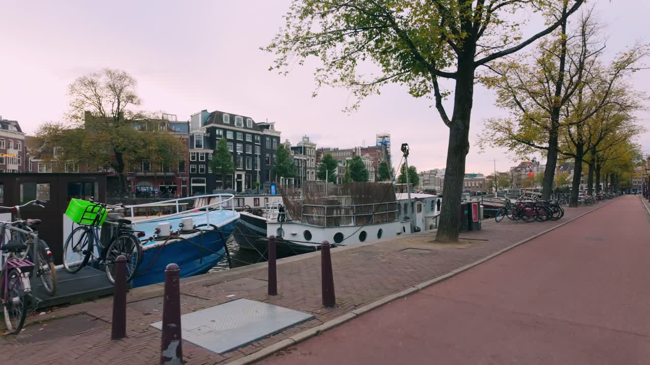 Scenic view of a canal path lined with houseboats and bicycles in Amsterdam, capturing the autumn atmosphere and iconic Dutch architecture. Amsterdam, Netherlands (Amsterdam, Nederland).
