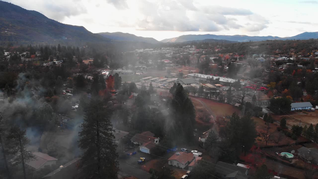 Aerial view of chimney smoke over a mountain neighborhood during winter time