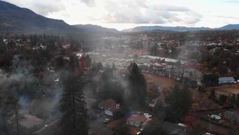Aerial-view-of-chimney-smoke-over-a-mountain-neighborhood-during-winter-time