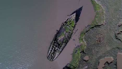 Drone-Ascending-Over-Ruined-Ship-In-Salt-Marshes-At-Tollesbury-Marina,-Essex,-United-Kingdom