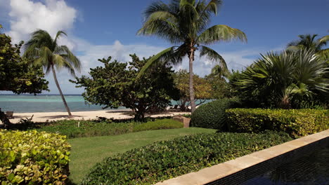 luxury tropical hotel resort with swimming pool, palm trees and white sand beach drone shot