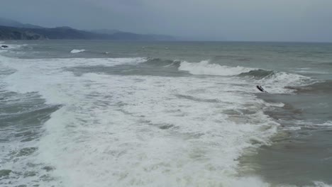 Olas-Rompiendo-En-La-Playa-De-Itzurun-En-Cámara-Lenta,-Plataforma-Aérea-Inversa